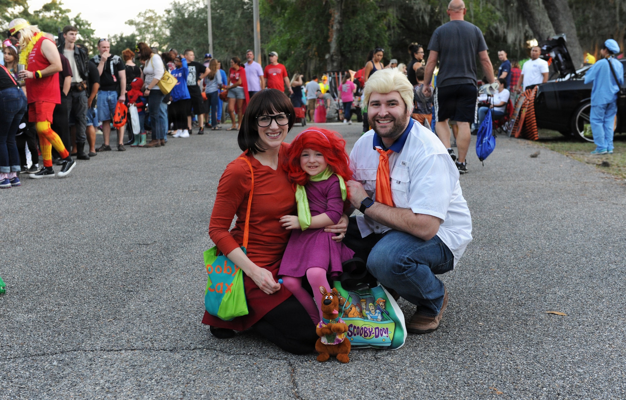 A woman, a child, and a man dressed up as scooby doo characters pose for a photo.