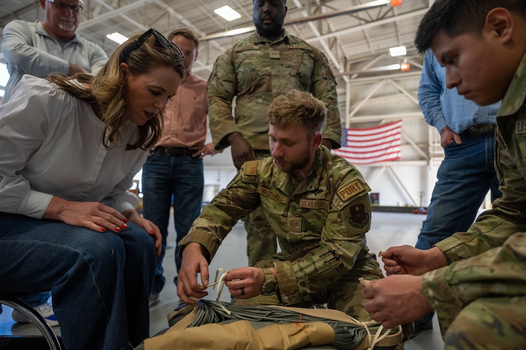U.S. Air Force Airmen assigned to the 97th Logistics Readiness Squadron teach honorary commanders how to prepare parachutes for heavy equipment during an immersion tour at Altus Air Force Base, Oklahoma, Feb. 6, 2026. The demonstration provided a hands-on look at airdrop rigging procedures and how the wing supports global mobility operations. (U.S. Air Force photo by Airman 1st Class Nathan Langston)