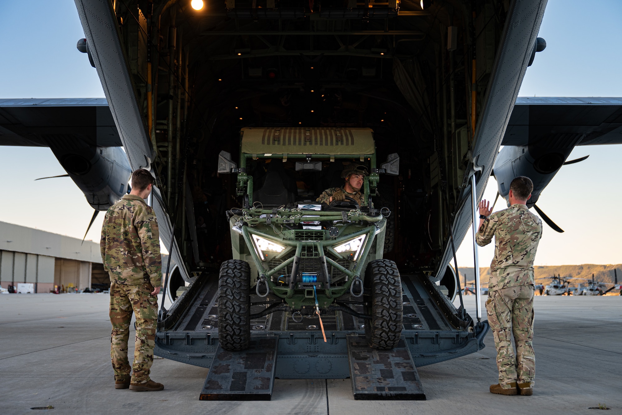 U.S. Marine Corps Lance Cpl. Talon Gardener, Marine Wing Support Squadron 372 expeditionary fuels technician, center, reverses an ultra-light tactical vehicle equipped with a Tactical Air Ground Refueling Systems onto a C-130J Super Hercules assigned to the 40th Airlift Squadron, as U.S. Air Force Senior Airman Matthew Monville and Master Sgt. Andy Cline, both 40th AS loadmasters, assist during the Spring 2026 C-130 Weapons System Council at Marine Corps Base Camp Pendleton, California, Feb. 4, 2026. During the WSC, Airmen conducted Specialized Fueling Operations training with I Marine Expeditionary Force. (U.S. Air Force photo by Senior Airman Jade M. Caldwell)