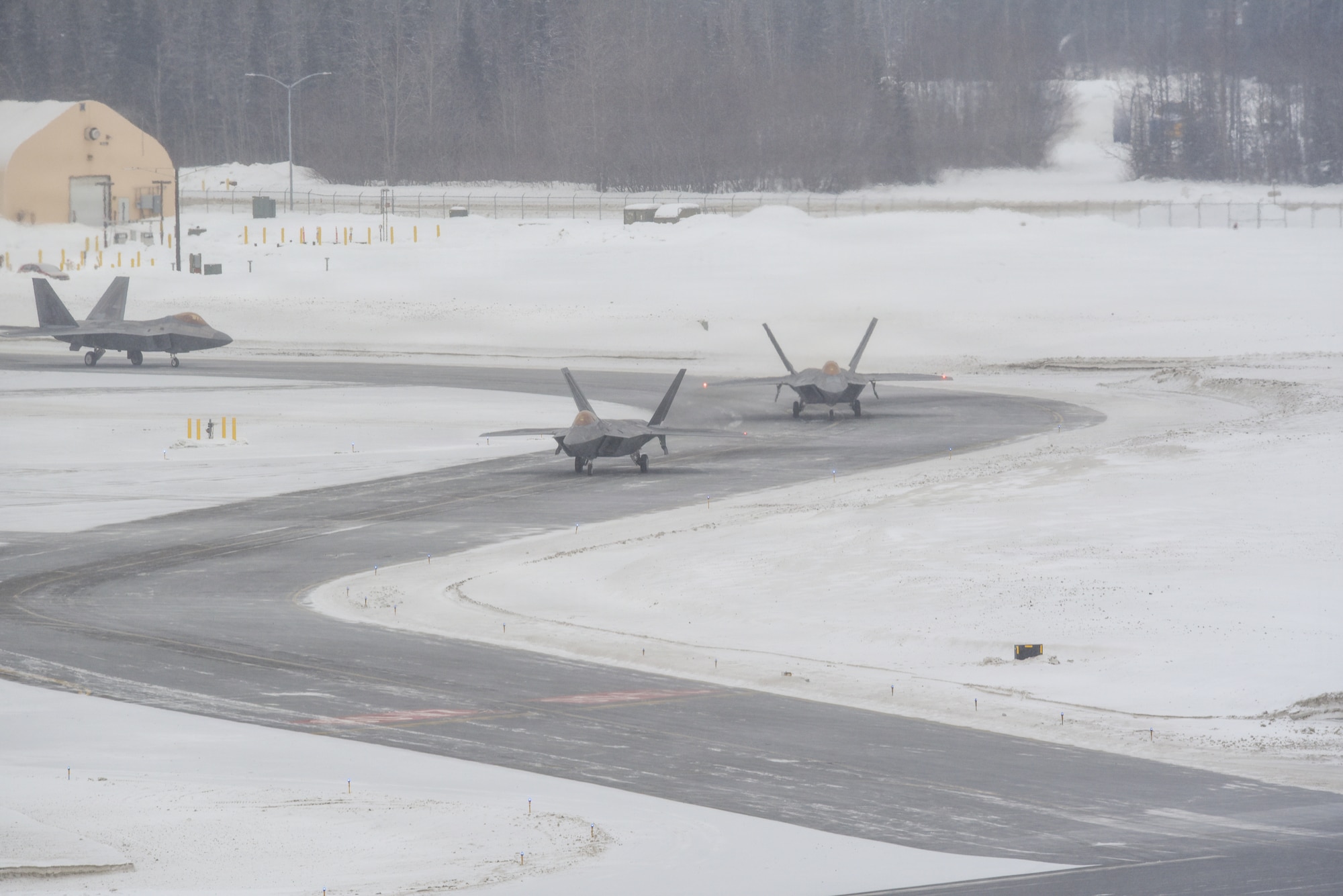 U.S. Air Force F-22 Raptors assigned to the 3rd Wing taxi down the flight line during snowfall at Joint Base Elmendorf-Richardson, Alaska, Feb. 10, 2026. The F-22 Raptor is designed to project air dominance and cannot be matched by any known or projected fighter aircraft, providing power projection across the Indo-Pacific region. (U.S. Air Force photo by Nicholas Holland)