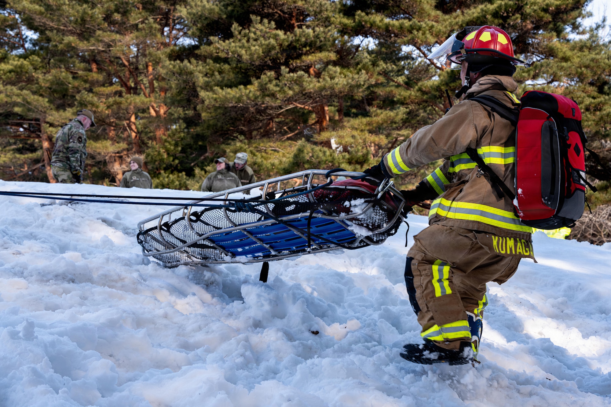 Tadakatsu Kumagai, 35th Civil Engineer Squadron (CES) firefighter, pulls a stretcher downhill to a simulated car wreck during an inter-unit casualty and vehicle recovery exercise.