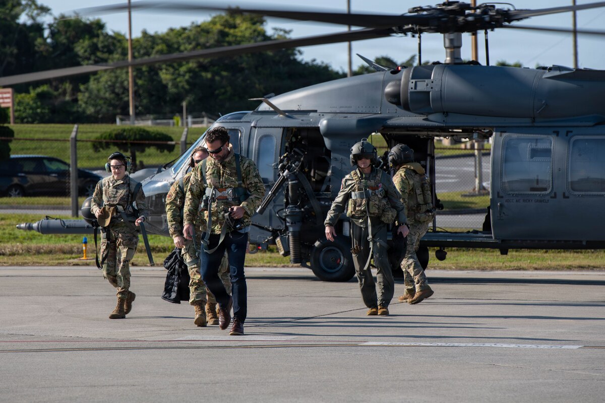 Government official and service members step off helicopter.