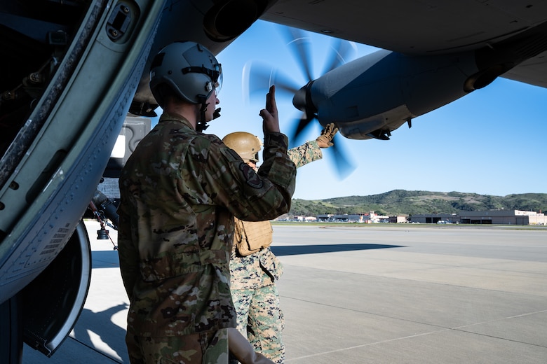 U.S. Air Force Senior Airman Matthew Monville, 40th Airlift Squadron loadmaster, signals the upload of fuel during a hot-pit refuel at Marine Corps Base Camp Pendleton, California, Feb. 4, 2026. The Specialized Fueling Operation supported joint training between the I Marine Expeditionary Force and 317th Airlift Wing during the Spring 2026 C-130 Weapon System Council. (U.S. Air Force photo by Senior Airman Jade M. Caldwell)
