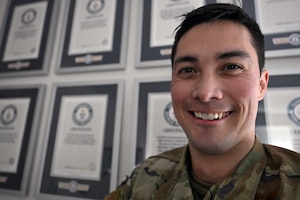 Maj. Jonathan Buckingham poses in front of a wall of Guinness World Records he achieved here, Feb. 4, 2026. Buckingham has set 17 Guinness World Records and has three submissions pending review. Buckingham is a program manager with the Department of the Air Force Portfolio Acquisition Executive for Command, Control, Communications and Battle Management’s Kessel Run division. (Official Air Force Photo by Richard Blumenstein).