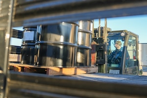 Man loads hazardous waste drums onto a truck