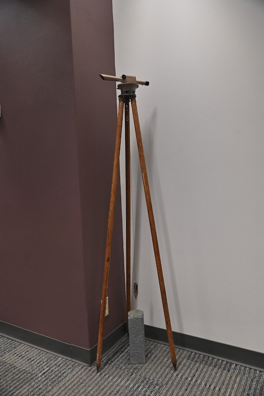 The United States Army Corps of Engineers’ Fort Worth District Real Estate Division has several antique survey instruments on display. Here, a transit sits atop a wooden tripod with a plumb bob centered over a survey marker. The transit is a telescope that can rotate horizontally and vertically on precise calibrated circles. It’s used for measuring angles between two fixed points. The plumb bob is used to find a true vertical line through the force of gravity. It is an essential tool for ensuring structures are built straight up and down in construction, masonry, surveying, and countless other tasks where precision alignment is critical. A survey marker is a permanent object placed to mark a precisely surveyed point on the earth’s surface. It can be used as a fixed reference point by future surveyors to ensure accuracy and consistency in measuring land.