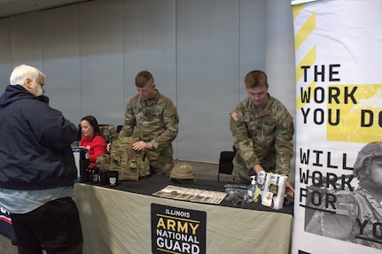 Spc Daniel Mantel (left) and Spc Christian Lis (right), military police with the 933rd Military Police Company, help set up the Illinois National Guard booth at the Chicago Auto Show.