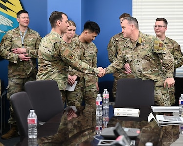 ACC Command chief shakes Airman's hand in a conference room.