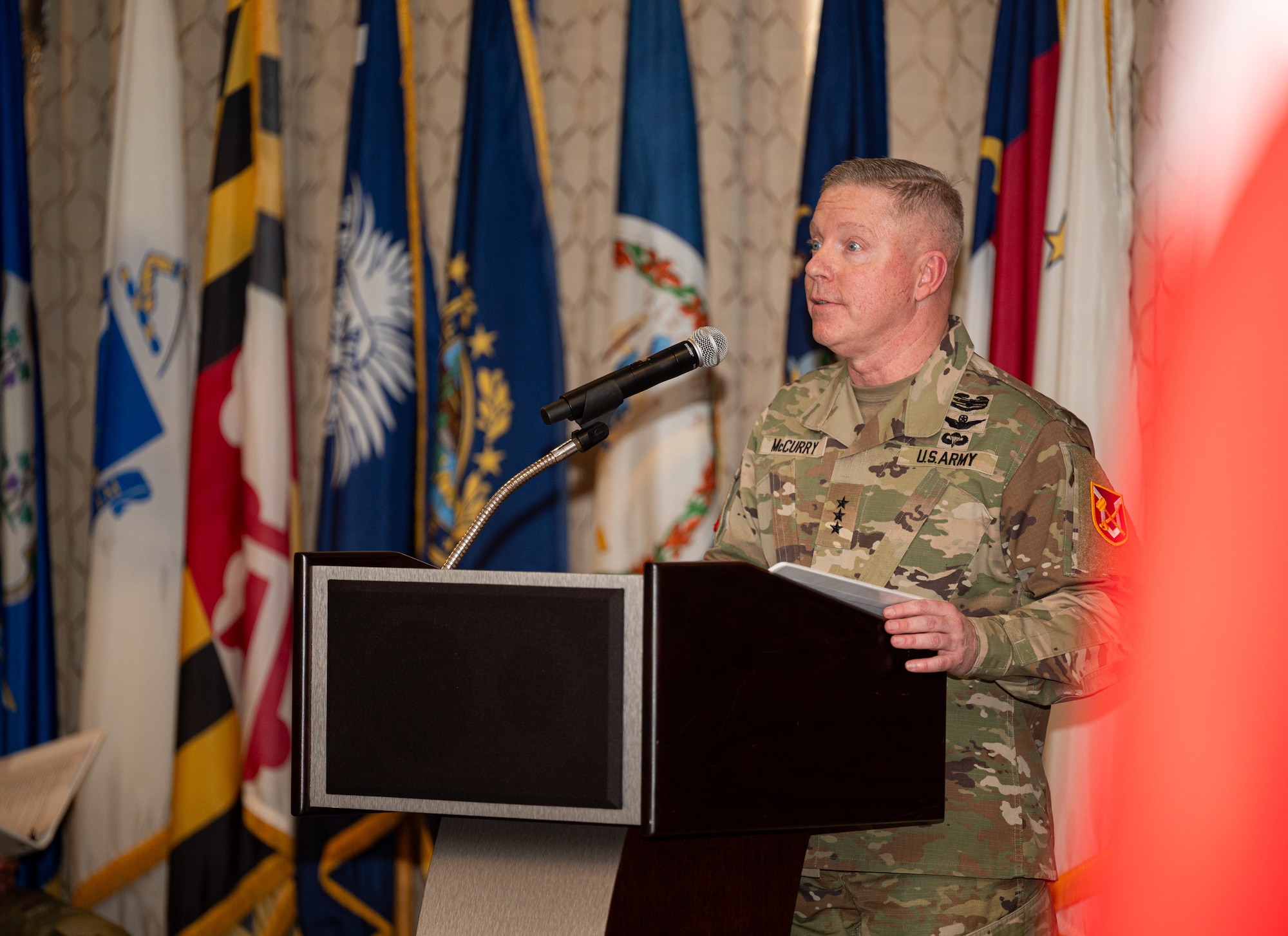 A soldier stands at a podium with a mic
