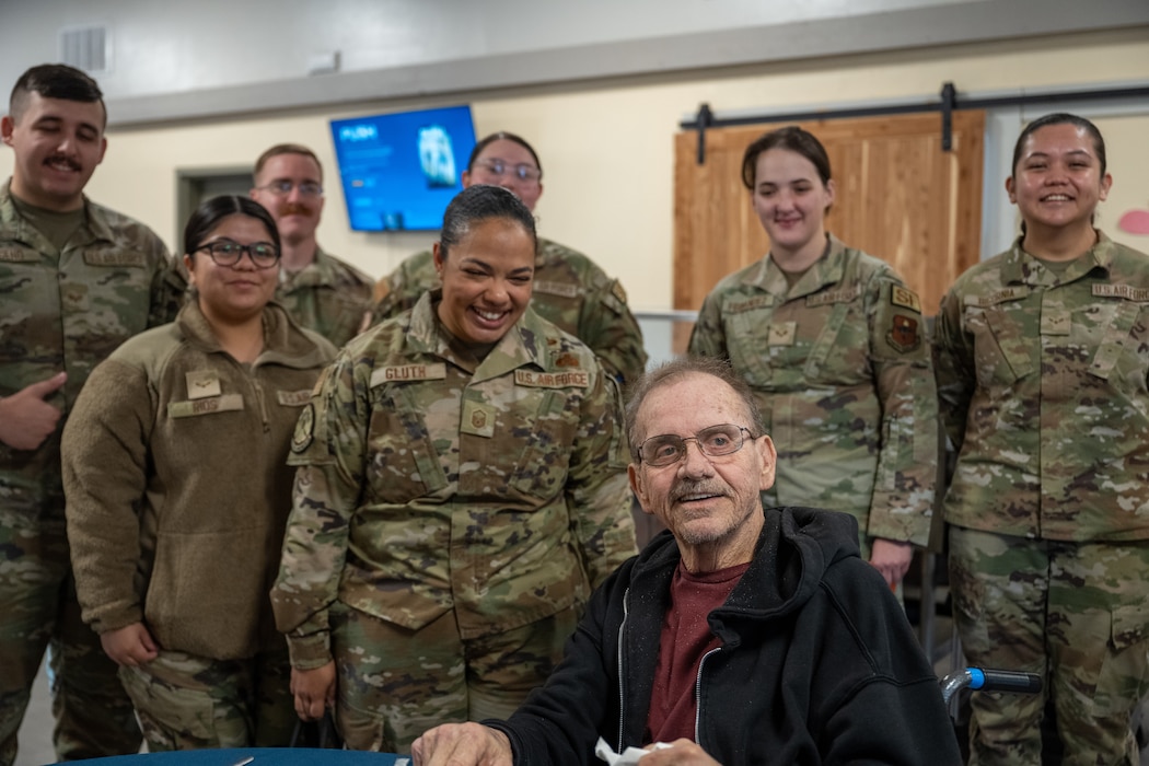 U.S. Air Force Airmen from the 97th Air Mobility Wing smile with a veteran at English Village Manor in Altus, Oklahoma, Feb. 10, 2026. The Airmen volunteered to deliver Valentine’s Day cards to local veterans as a gesture of appreciation and community support. (U.S. Air Force photo by Airman 1st Class Nathan Langston)