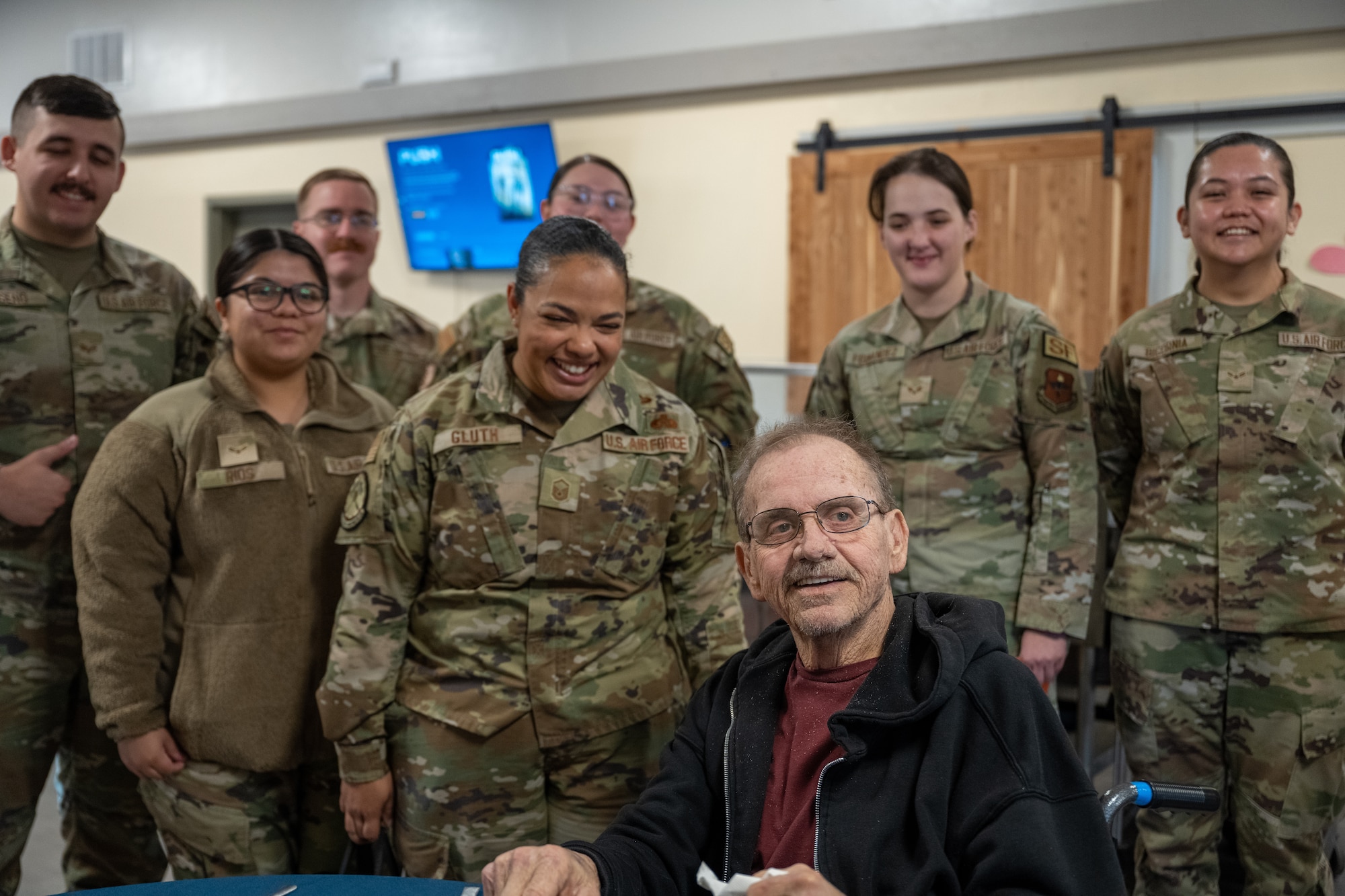U.S. Air Force Airmen from the 97th Air Mobility Wing smile with a veteran at English Village Manor in Altus, Oklahoma, Feb. 10, 2026. The Airmen volunteered to deliver Valentine’s Day cards to local veterans as a gesture of appreciation and community support. (U.S. Air Force photo by Airman 1st Class Nathan Langston)