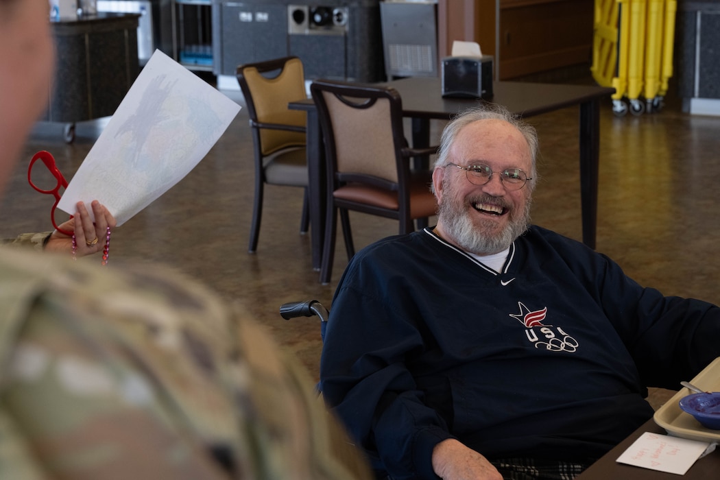 A veteran smiles at an Altus Air Force Base Airman at Clinton Veterans Home in Clinton, Oklahoma, Feb. 10, 2026. Altus Air Force Base Airmen visited with veterans and delivered valentines made by students at L. Mendel Rivers Elementary School, thanking them for their service. (U.S. Air Force photo by Airman 1st Class Emma Wright)