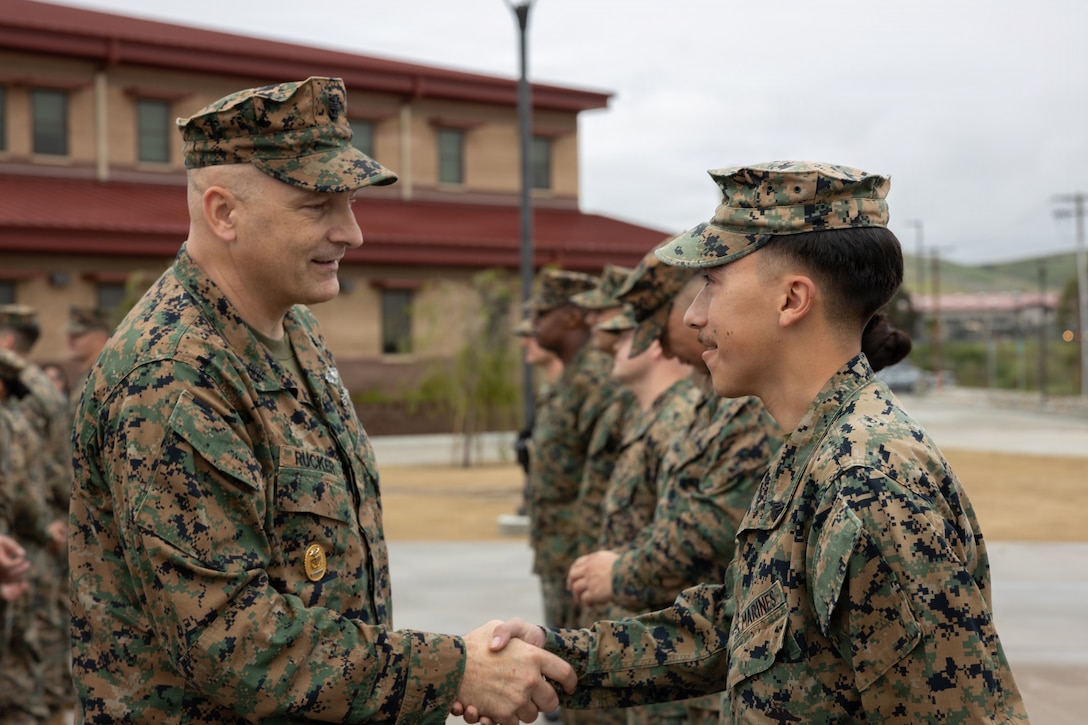 U.S. Navy Master Chief Loren D. Rucker, command master chief, I Marine Expeditionary Force, left, presents a challenge coin to Marine Corps Sgt. Roberto Chaveznajar, a network administrator, 9th Communication Battalion, I Marine Expeditionary Force Information Group, during a coin presentation and recognition ceremony at Marine Corps Base Camp Pendleton, Calif., Feb. 11, 2026. The ceremony recognized more than 30 Marines and Sailors for their hard work and dedication during the preparation and execution of the 250th Amphibious Capabilities Demonstration and Beach Bash held Oct. 18, 2025. Chaveznajar was recognized for establishing network services aboard the USS Boxer (LHD 4), which enabled effective command and control from ship to shore. (U.S. Marine Corps photo by Sgt. Dillon Buck)