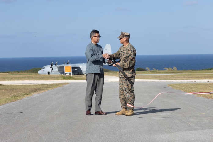Masaru Murai, director general of the Okinawa Defense Bureau, and U.S. Marine Corps Maj. Gen. Brian Wolford shake hands during a ribbon cutting ceremony at Ie Shima Training Facility, Okinawa, Japan, Dec. 15, 2025.