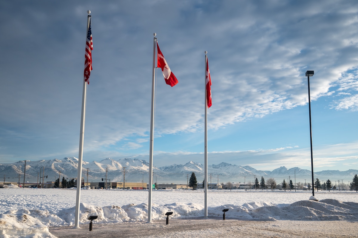 The national flags of the United States, Canada and Denmark are displayed outside the Elmendorf Professional Military Education Center on Joint Base Elmendorf-Richardson, Alaska, Jan. 21, 2026. The Elmendorf PME Center welcomed members of the Canadian and Danish armed forces to be part of Noncommissioned Officer Academy. The inclusion of the Canadian and Danish flags outside the Elmendorf PME Center symbolizes the integration of foreign military perspectives into the joint training environment. (U.S. Air Force photo by Airman 1st Class Theodore Gowdy)