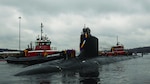 U.S. Navy nuclear submarine being guided by tugboats