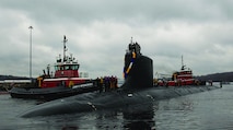 U.S. Navy nuclear submarine being guided by tugboats