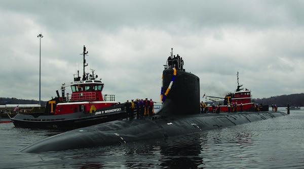 U.S. Navy nuclear submarine being guided by tugboats