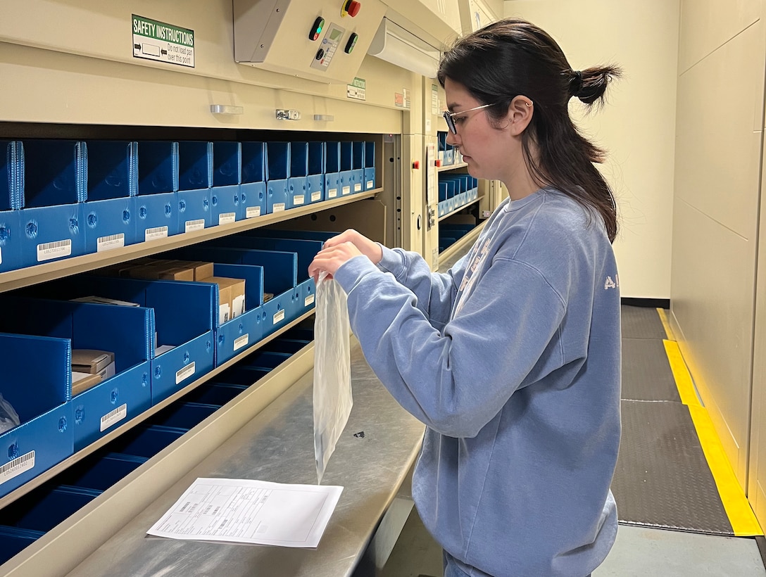 A woman reviews an order for a repair part in a clear plastic bag.