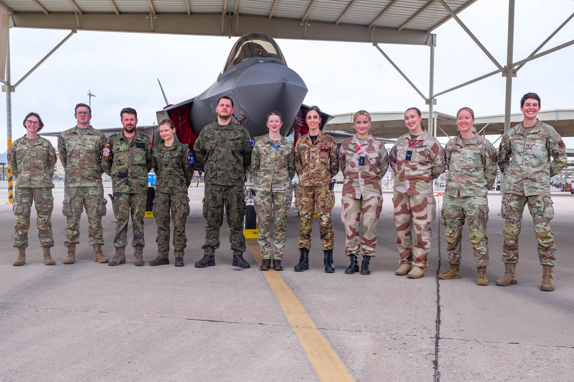 F-35 International Intelligence Formal Training Unit graduates and instructors, pose for a photo in front of an F-35A Lightning II, Feb. 11, 2026, at Luke Air Force Base, Arizona. The F-35 IIFTU provides advanced instruction to intelligence professionals from partner nations, delivering a comprehensive understanding of the F-35’s operational capabilities and tactical employment. The graduating class was the most diverse in the unit’s history, consisting of seven students representing five partner nations. (U.S. Air Force photo by Airman 1st Class Tekorey Watkins)