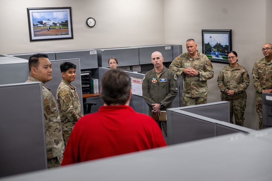 Photo of people standing in a cubicle.