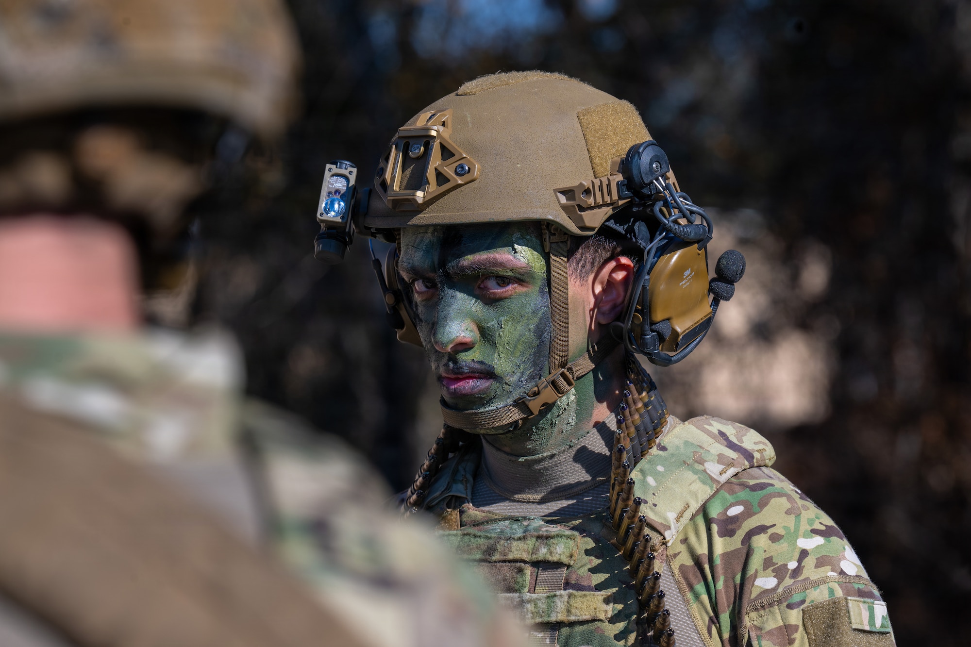 Photo of someone wearing camo paint looking into camera.