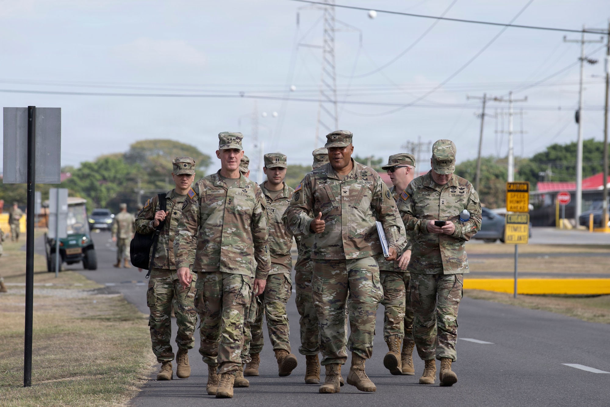 Military members walk down a road.