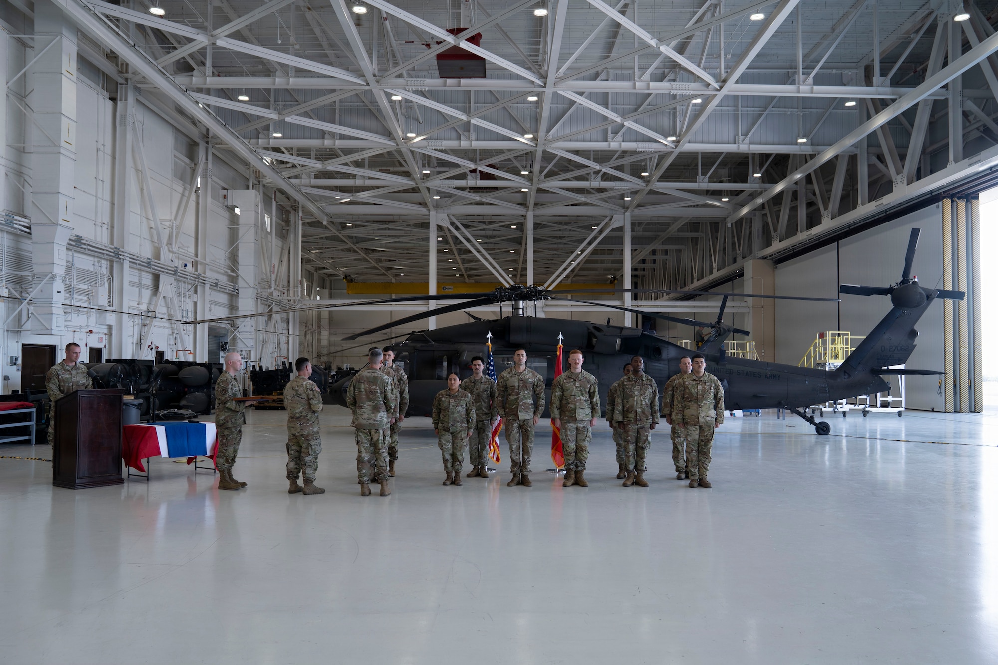 Military members line up in formation in front of a helicopter