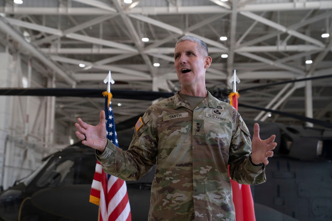A high ranking military officer talks in front of a helicopter and national flags