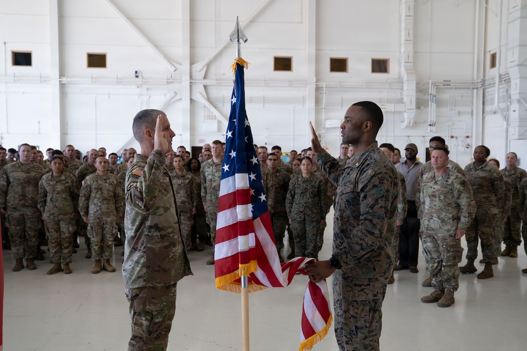 people in military uniforms stand for a ceremony with an American flag in the middle.