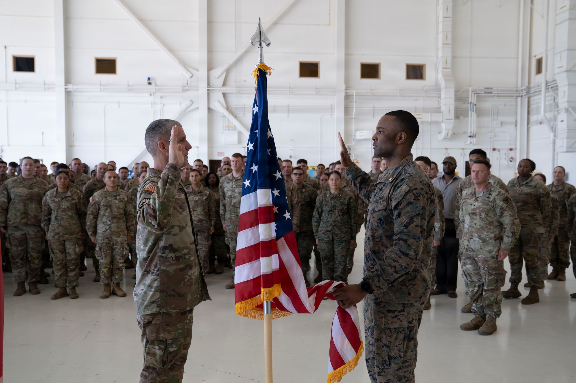 people in military uniforms stand for a ceremony with an American flag in the middle.
