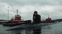 U.S. Navy nuclear submarine being guided by tugboats