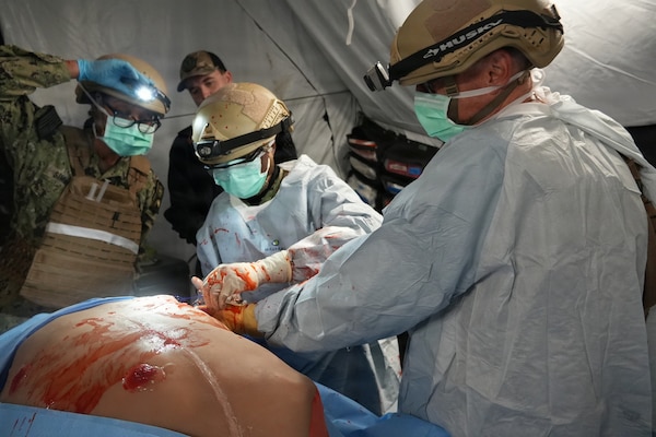 Capt. Ernest Block (right), a general surgeon, Cmdr. Ranata Simmons (left), a certified registered nurse anesthetist, and Hospital Corpsman 2nd Class Tatrelia Kunda (center), surgical technician, all assigned to Expeditionary Resuscitative Surgical System (ERSS) 21, Navy Reserve, conduct a simulated surgical procedure during an ERSS training evolution at Camp Pendleton, California, Jan. 19-30, 2026.  The training, conducted by Naval Expeditionary Medicine Warfighter Development Center (NEMWDC), highlights coordination, adaptability, and resource management in expeditionary medical operations.  (U.S. Navy photo by Petty Officer 2nd Class Moira Esquivel)