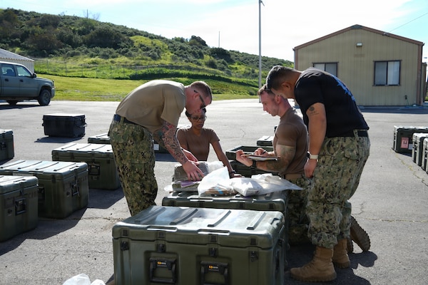 Cmdr. Ranata Simmons(back left),, a certified registered nurse anesthetist Lt. Ryan Buyeske (back right), an emergency room nurse, and Hospital Corpsman 3rd Class Rian Meeks (left), a respiratory therapist all assigned to Expeditionary Resuscitative Surgical System (ERSS) 21, Navy Reserve,  review equipment and supplies with Culinary Specialist 2nd Class Raymond Santiago(right) , an instructor assigned to the Naval Expeditionary Medicine Warfighter Development Center (NEMWDC) during an ERSS training evolution at Camp Pendleton, California, Jan. 19-30, 2026.  The training, conducted by NEMWDC, emphasizes planning, accountability, and resource management in austere environments where resupply may be limited.  (U.S. Navy photo by Petty Officer 2nd Class Moira Esquivel)