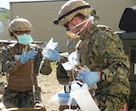 Cmdr. Ranata Simmons (left), a certified registered nurse anesthetist and Lt. Ryan Buyeske (right), an emergency room nurse, both assigned to Expeditionary Resuscitative Surgical System (ERSS) 21, Navy Reserve, prepare intravenous fluids during an ERSS training evolution at Camp Pendleton, California, Jan. 19-30, 2026.   The course, conducted by Naval Expeditionary Medicine Warfighter Development Center (NEMWDC), trains Sailors to adapt clinical care while conserving and prioritizing limited medical resources in expeditionary settings.  (U.S. Navy photo by Petty Officer 2nd Class Moira Esquivel)