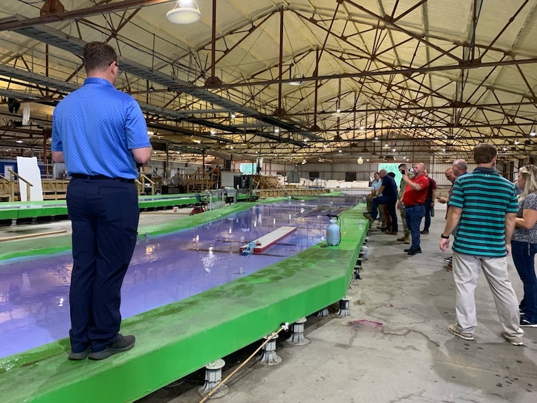 A man steers a remote controlled boat down a model river.