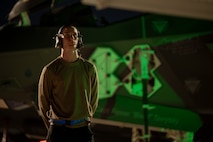 a maintainer in front of an aircraft at night