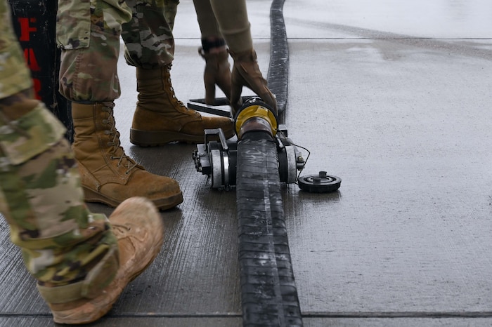 U.S. Air Force Airmen 1st Class Nicholas Beeson, 355th Logistics Readiness Squadron fuels distribution operator, places a fuel hose squeegee under a 300 foot collapsible fuel hose during Forward Area Refueling Point team tryouts at Davis-Monthan Air Force Base, Ariz., Feb. 13, 2026. The squeegee is used to remove fuel from the hose once rapid special forces refueling operations are complete. (U.S. Air Force photo by Staff Sgt. Kahdija Slaughter)