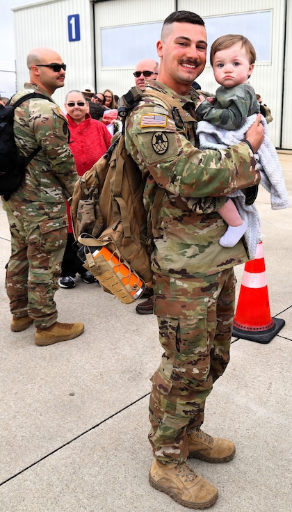 Illinois Army National Guard Spc. Wyatt Collier holds his son, 1-year-old Waylon Collier, after returning from deployment.