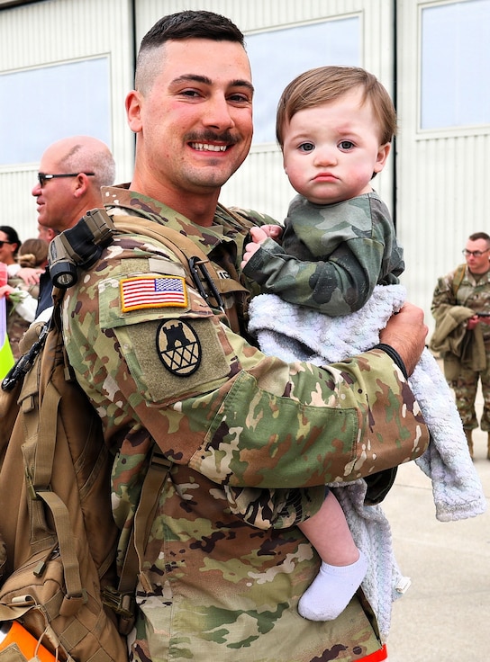 Illinois Army National Guard Spc. Wyatt Collier holds his son, 1-year-old Waylon Collier, after returning from deployment.