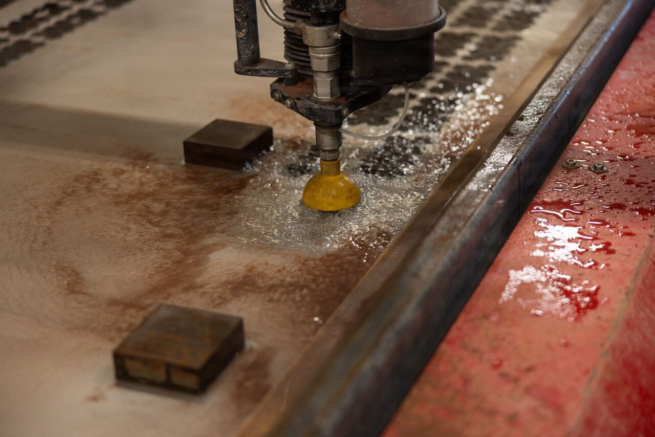 A piece of equipment cuts washers out of a large metal sheet. There are little pieces of metal all around the bottom of the machine.