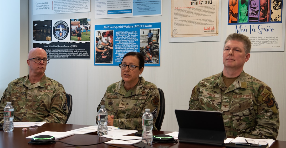 Three Airmen sit at a table during a town hall discussion.