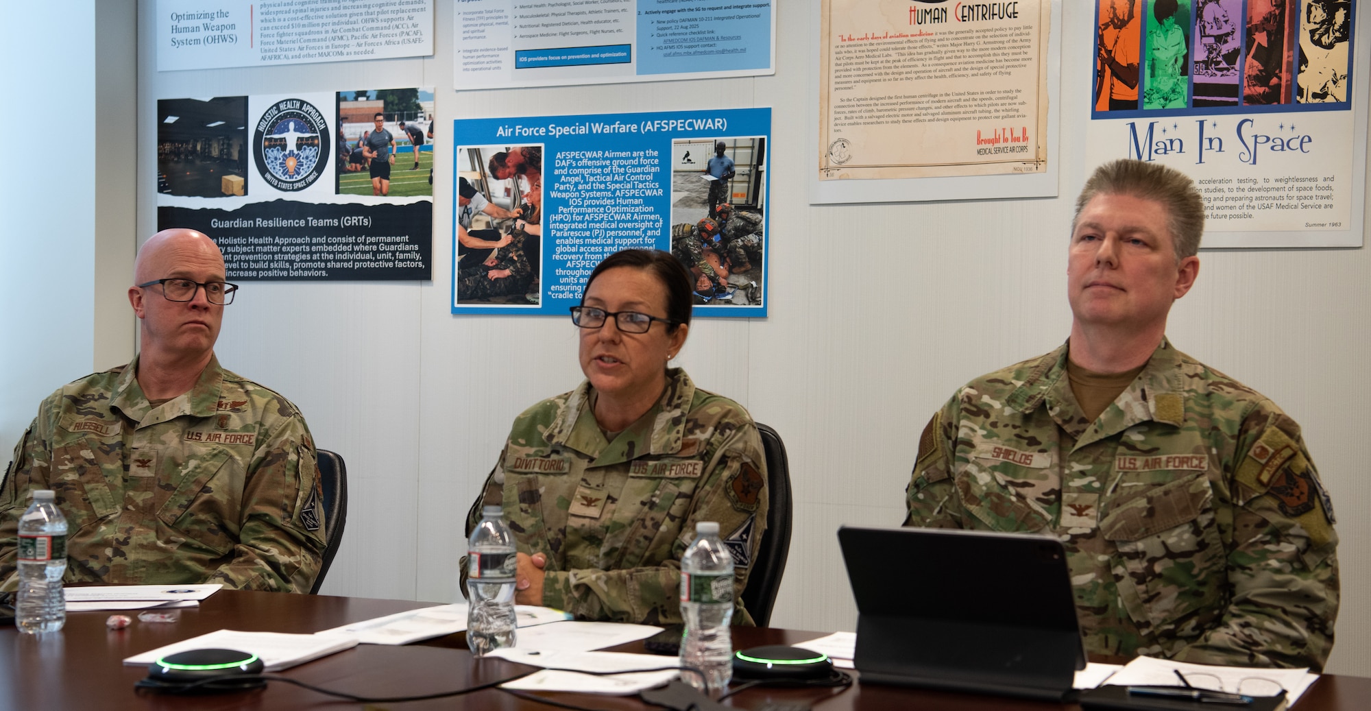 Image of three Airmen sitting at a table during a town hall discussion.