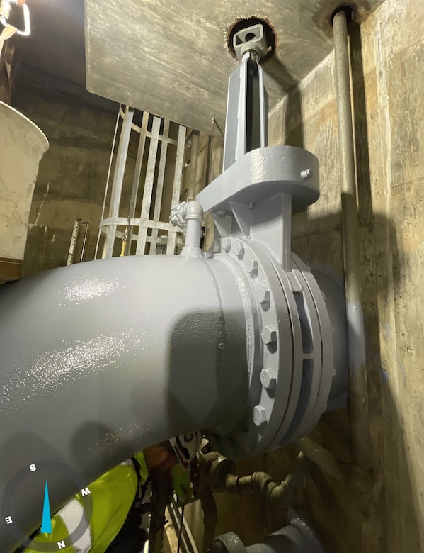 A large grey metal pipe with concrete walls in the background.