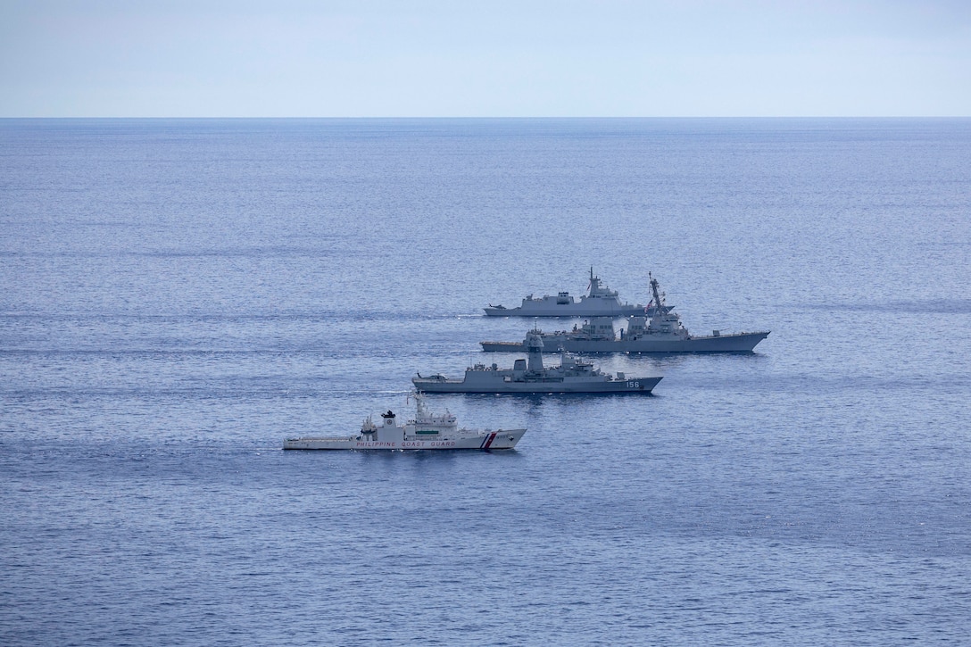 Four military vessels sail in formation at sea.