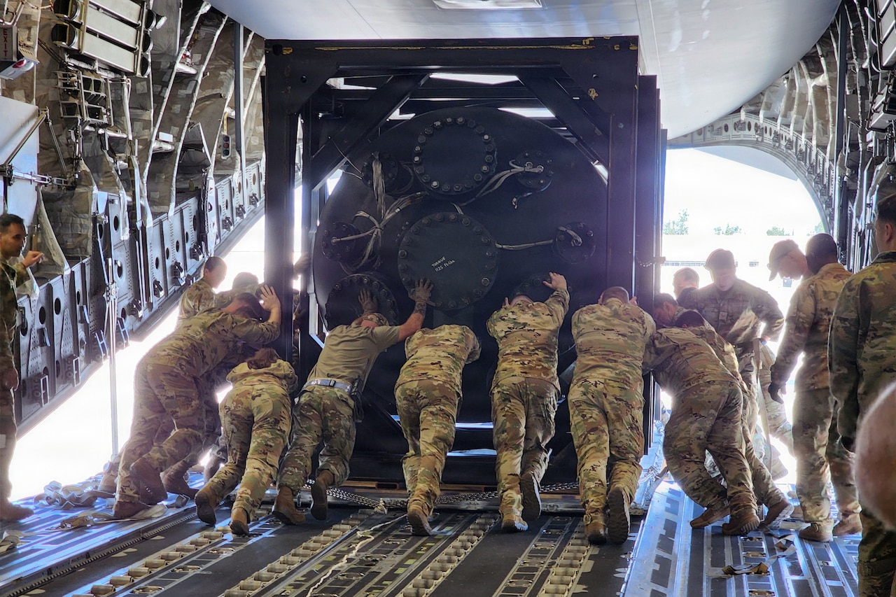 A nuclear reactor is carted to the back of an open aircraft.