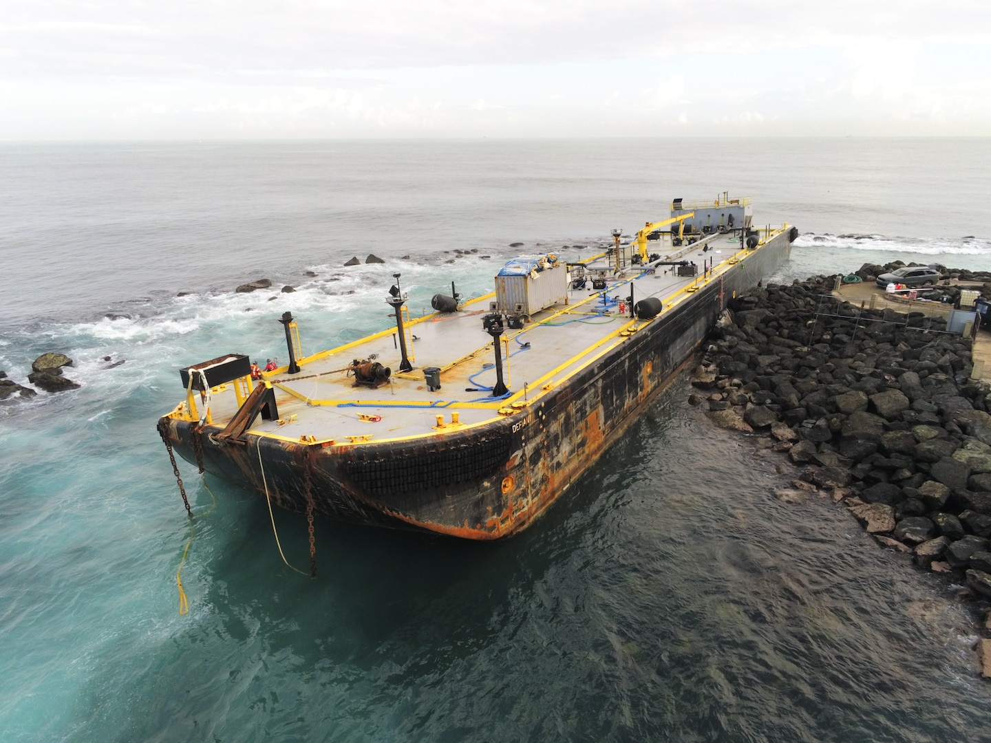 he 285-foot fuel barge, Defiant, sits aground along the rocks of Castillo San Felipe del Morro, Puerto Rico, Feb. 10, 2026. The Defiant went aground Feb. 9, 2026, after tug vessel Storm reported that their towline snapped within the San Juan Harbor. (U.S. Coast Guard courtesy photo)