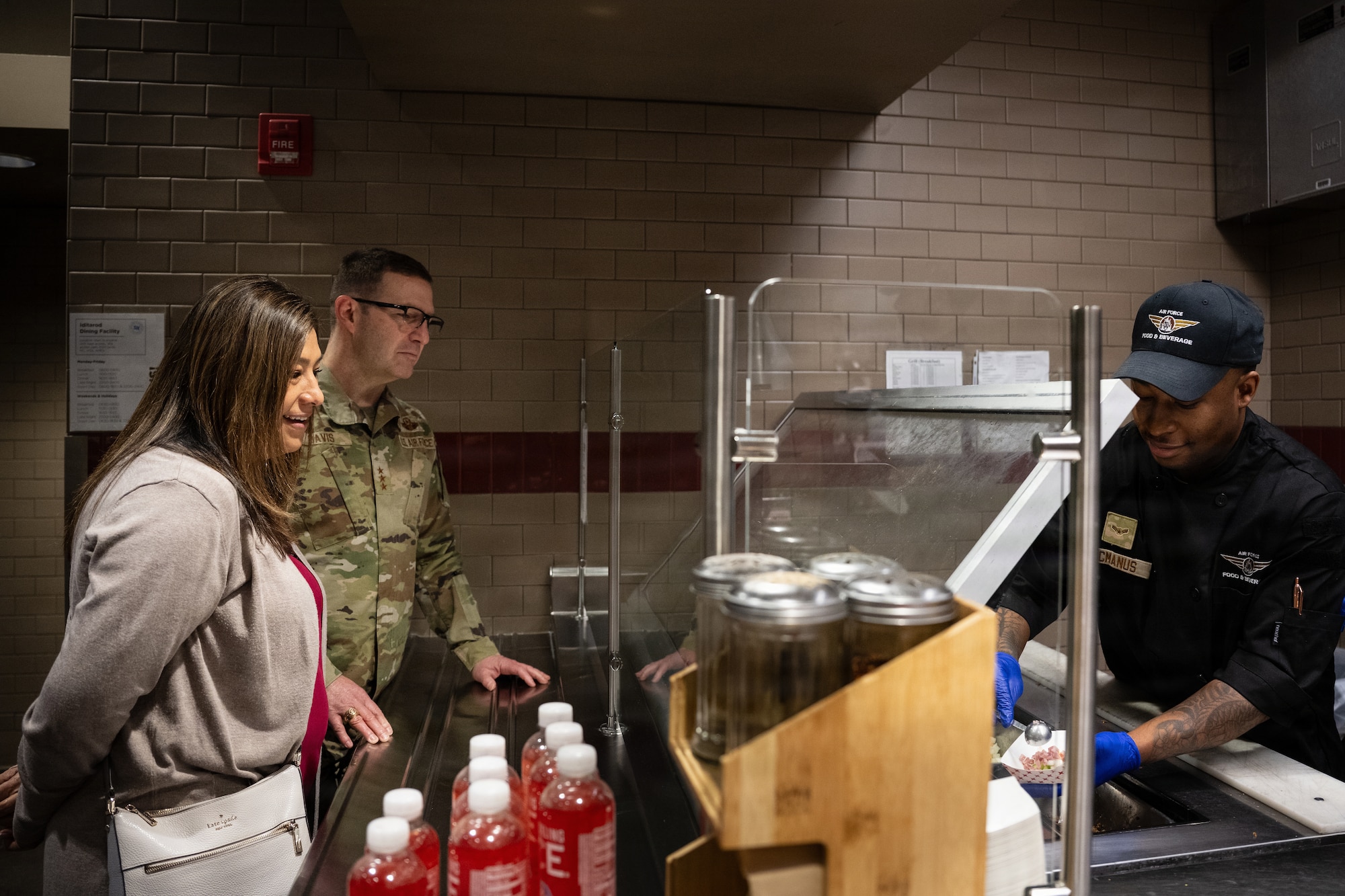 Kathy Davis and spouse U.S. Air Force Lt. Gen. Robert Davis, Alaskan NORAD Region, Alaskan Command and Eleventh Air Force, commander, speak with Airman 1st Class Damoni McManus, 673d Mission Support Group, food service apprentice, as he prepares breakfast at Joint Base Elmendorf-Richardson, Alaska, Feb. 9, 2026. McManus told the couple about his experiences on and off duty and life in the dormitories at JBER. Leaders and spouses visited facilities across the installation to boost morale and recognize the crucial role families play in supporting the force. (U.S. Air Force Photo by Airman Keola Vischi)
