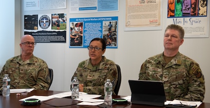 Image of three Airmen sitting at a table during a town hall discussion.
