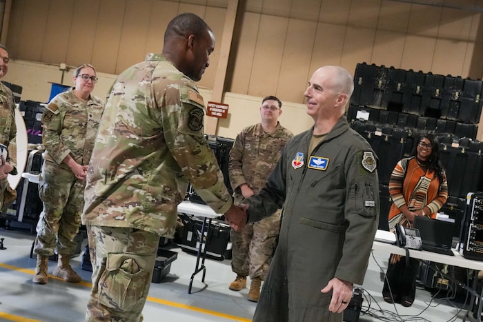 An Airman receives a coin from the 15th Air Force commander while other Airmen look on